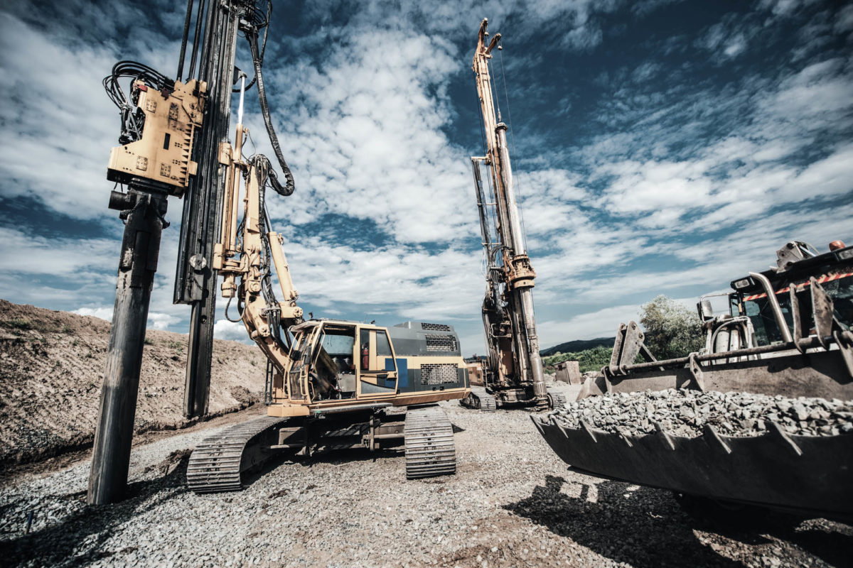 Highway construction site with heavy duty machinery. Two Rotary drills, bulldozer and excavator working